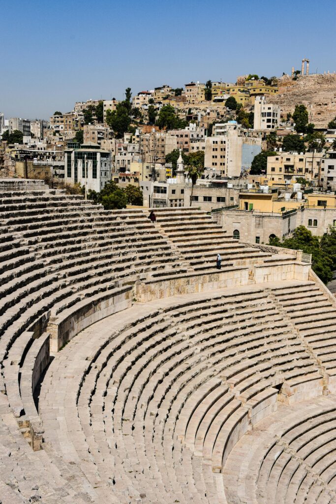 السياحة الأثرية في الأردن A view of the ancient Roman Amphitheater with modern Amman in the background, showcasing Jordanian history.