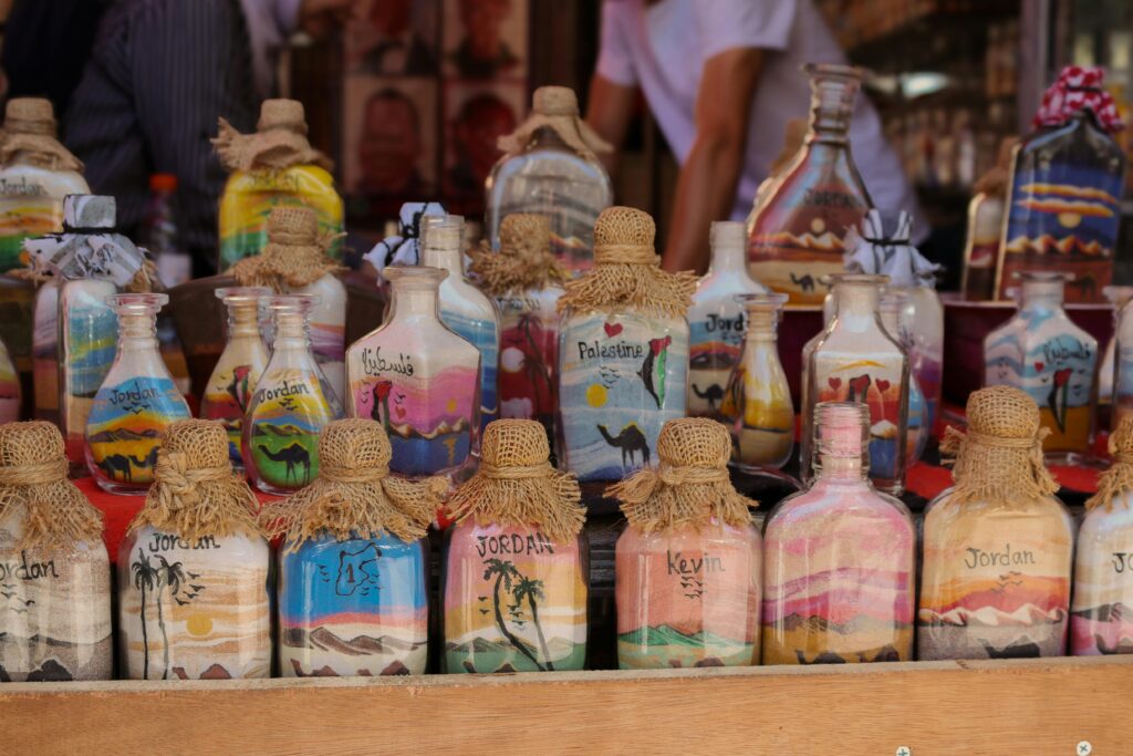 كنوز تراثية أردنية تقدم تجارب متنوعة لزوار دول الخليج Vibrant sand art bottles displayed in a Jordanian market stall showcasing local culture and souvenirs.